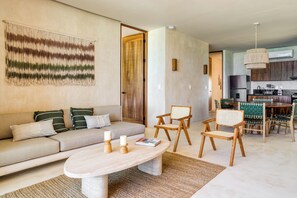 Una sala de estar moderna con un sofá, sillas, una mesa de centro y una zona de cocina con una mesa de comedor y sillas.
