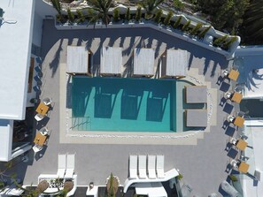 Vue aérienne d’un espace piscine avec des transats et une piscine centrale.