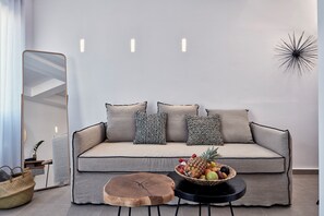 Un salon moderne avec un canapé, une table ronde en bois, un panier de fruits et un miroir.