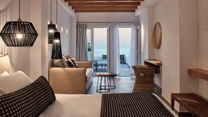 Ein modernes Hotelzimmer mit Bett, Sofa und Meerblick durch große Fenster.