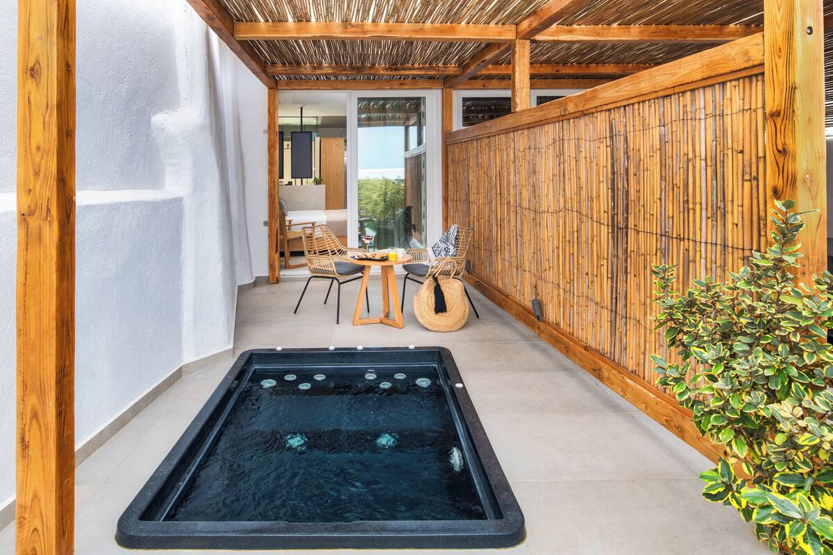 Uma área de spa com hidromassagem, deck de madeira e espaço para sentar.