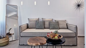 Ein modernes Wohnzimmer mit einer Couch, einem runden Holztisch, einer Obstschale und einem Spiegel.