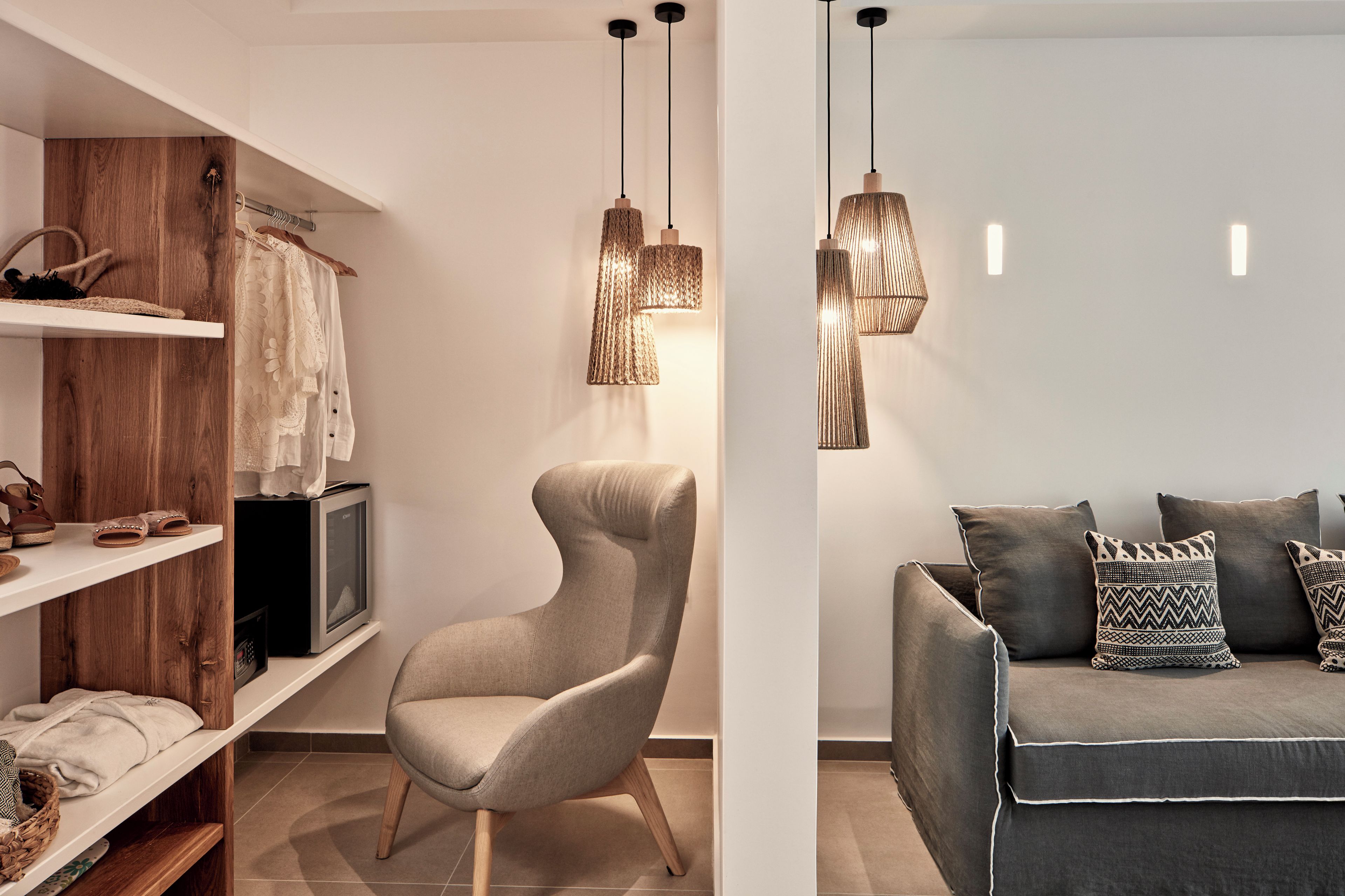 A modern living room with a grey sofa, patterned cushions, and pendant lighting.