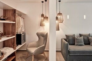 A modern living room with a grey sofa, patterned cushions, and pendant lighting. - Callia Retreat Suites (Santorini)