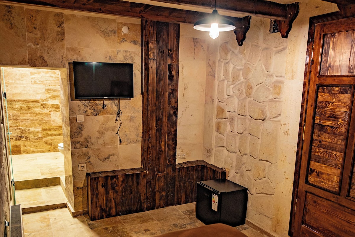 Une chambre à coucher avec un lit, un téléviseur fixé au mur et une armoire en bois.