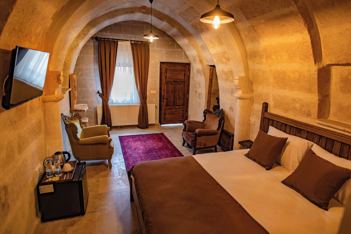 Une chambre d’hôtel avec un grand lit, une chaise, un bureau avec une lampe et un téléviseur fixé au mur.