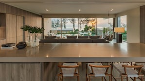 A modern kitchen with a large island, bar stools, and a seating area with cushions. - Veyla Natai Residences (Takua Thung)