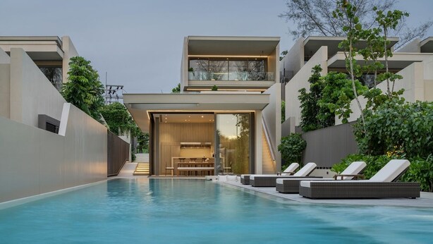 A modern poolside area with a clear view of the pool, lounge chairs, and a two-story building with a glass entrance. - Veyla Natai Residences (Takua Thung)