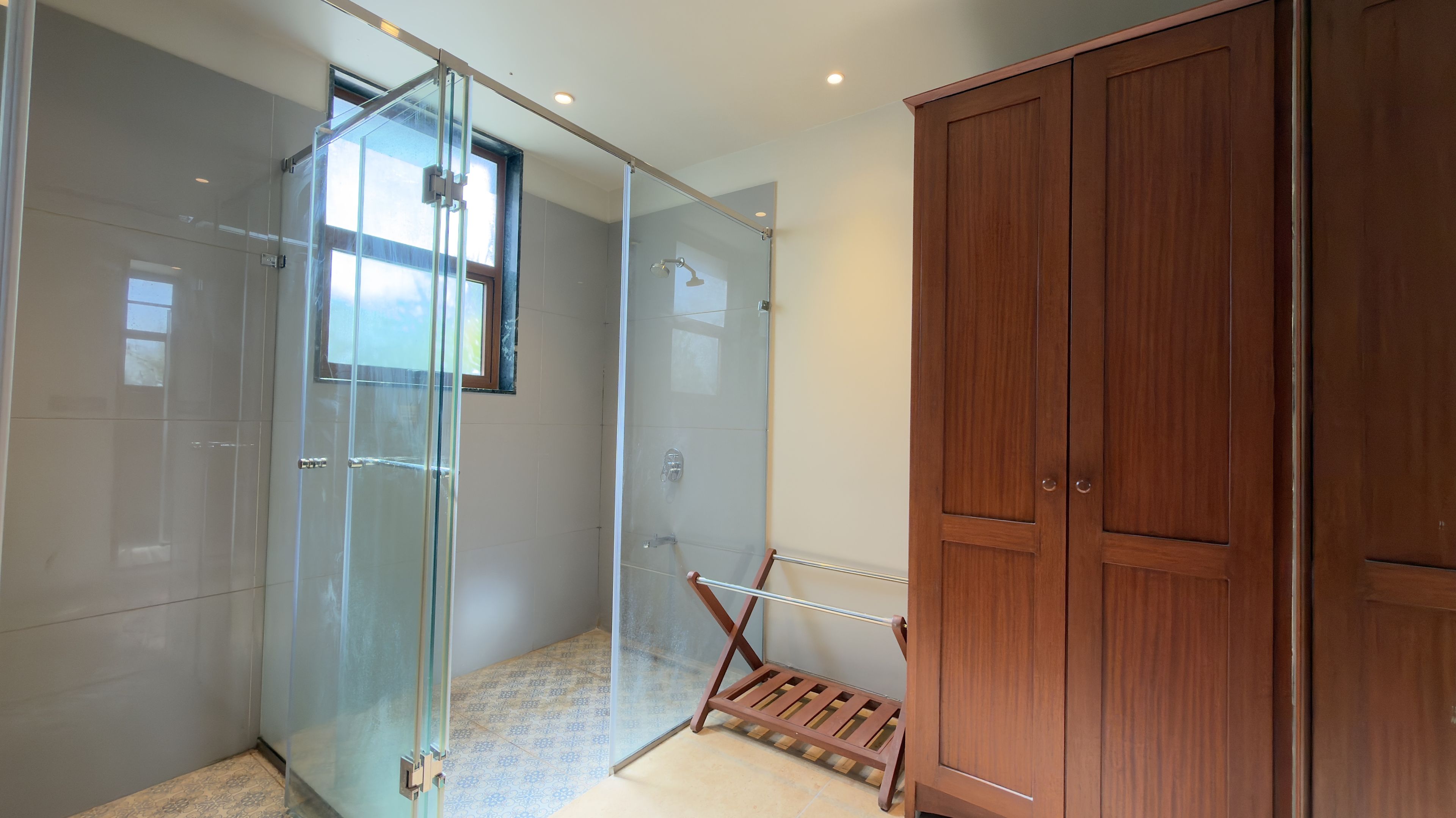 Un baño moderno con cabina de ducha de vidrio, armario de madera y un tendedero pequeño.