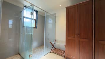 Un baño moderno con cabina de ducha de vidrio, armario de madera y un tendedero pequeño.