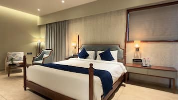 A hotel room with a large bed, bedside tables, a chair, and a desk.