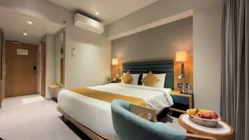 A hotel room with a bed, bedside table, lamp, and a fruit basket.