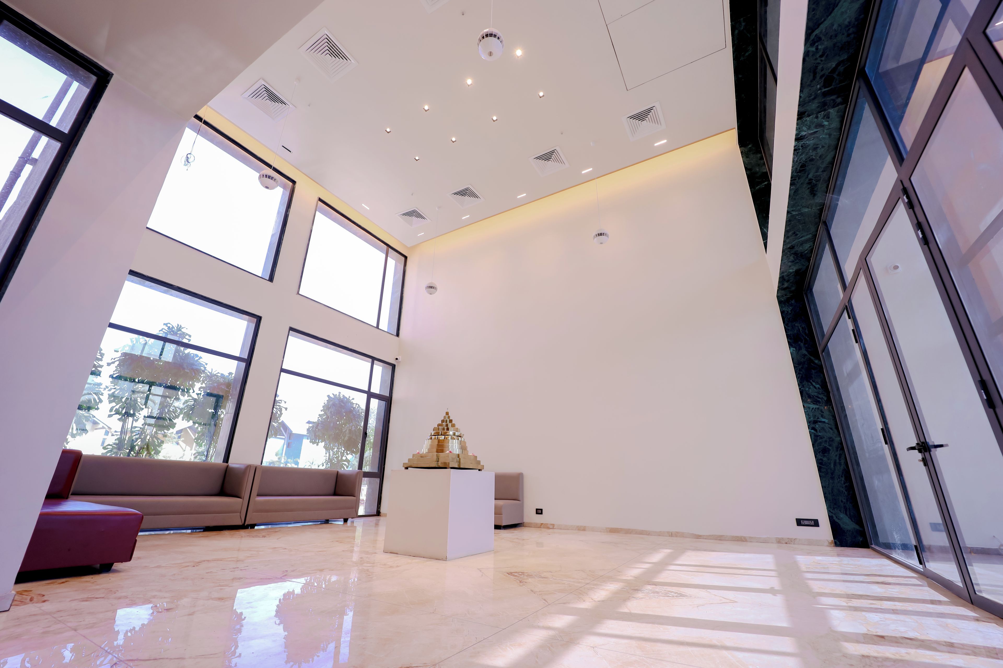 A spacious room with large windows, a white sofa, a small white table, and a glass door.
