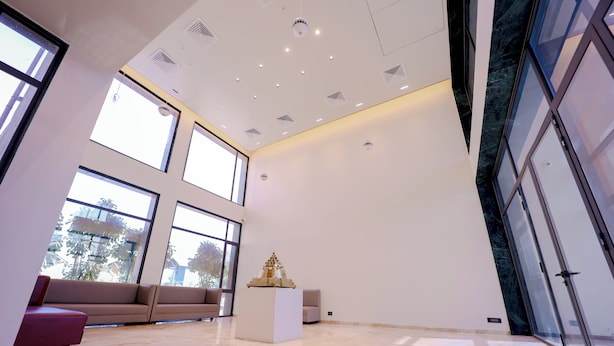 A spacious room with large windows, a white sofa, a small white table, and a glass door.