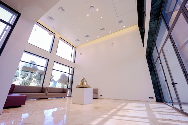A spacious room with large windows, a white sofa, a small white table, and a glass door. - Vinti Resort (Danta)