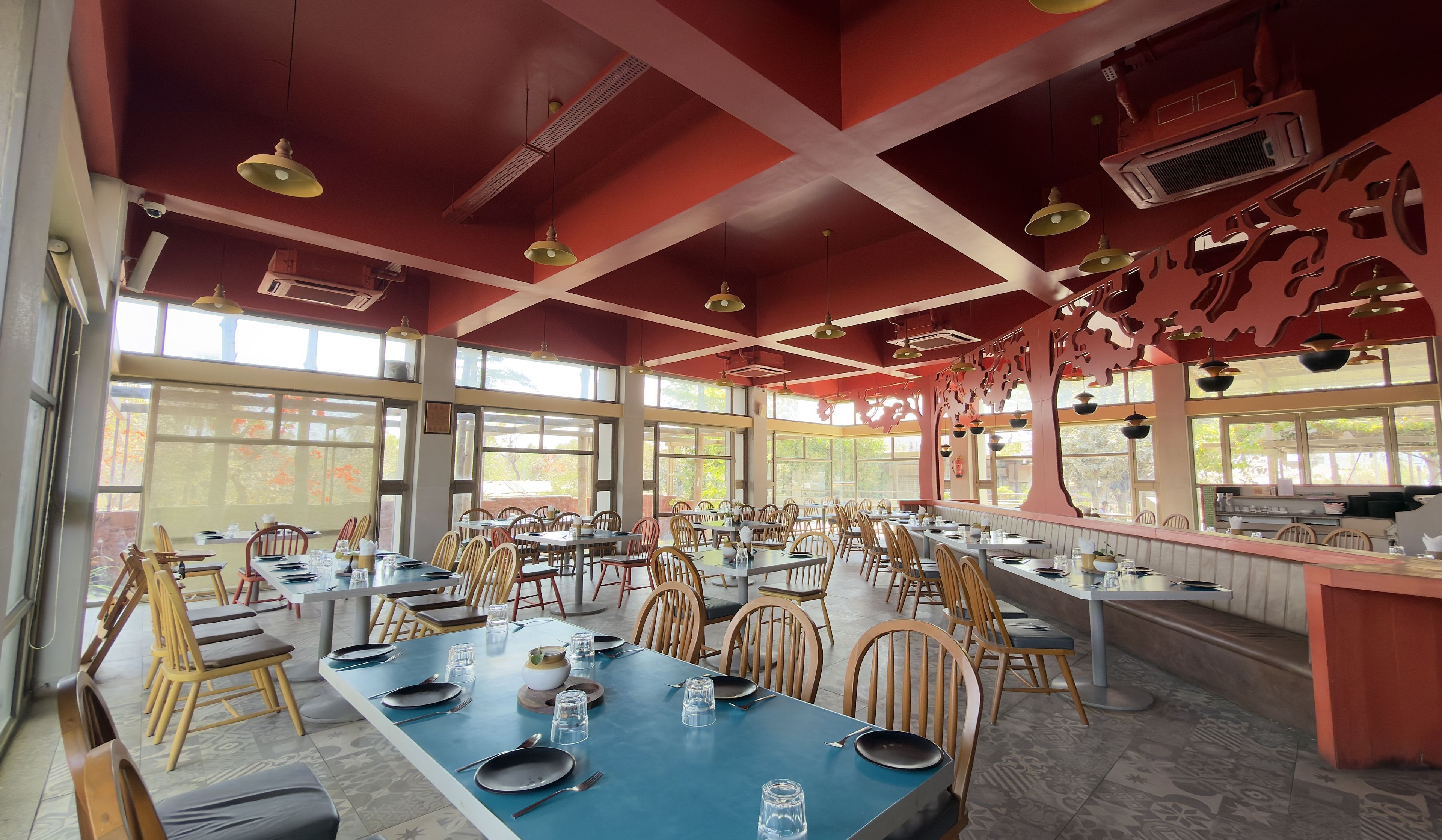 A spacious restaurant with high ceilings, large windows, and a variety of seating arrangements.