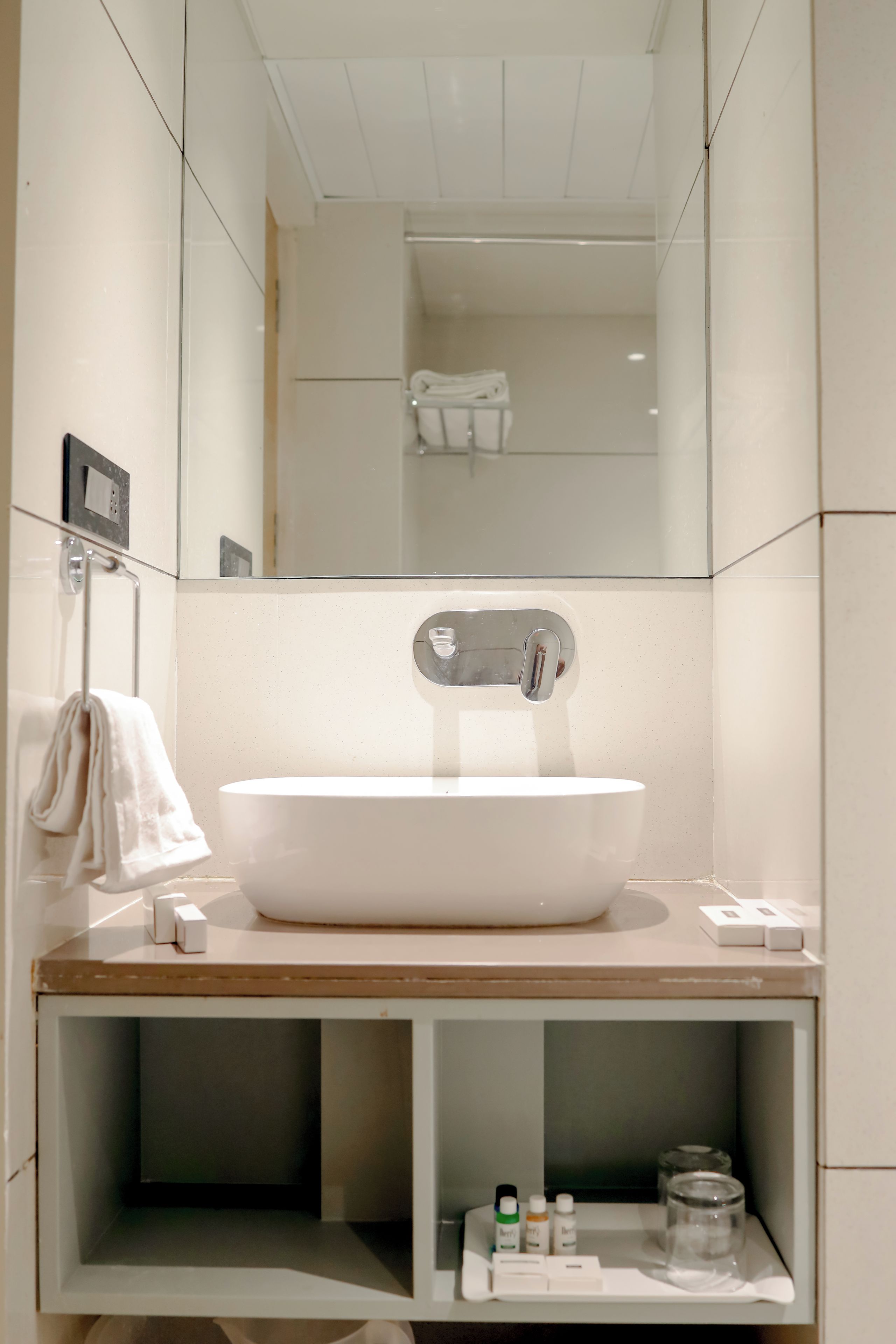 A modern bathroom with a large white sink, a mirror, and a towel rack.