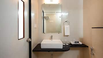 A bathroom with a white sink, a mirror, a towel rack, and a shower area.