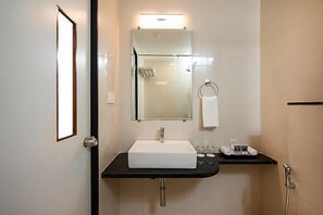 Casa de banho com lavatório branco, espelho, porta-toalhas e zona de duche.