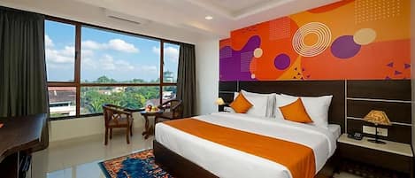 Habitación de hotel con una cama grande, un escritorio, una silla, vistas a la ciudad y un diseño de pared colorido.