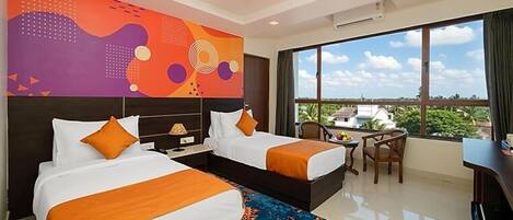 A hotel room with two beds, a desk, a chair, a large window with a view, and a ceiling fan.