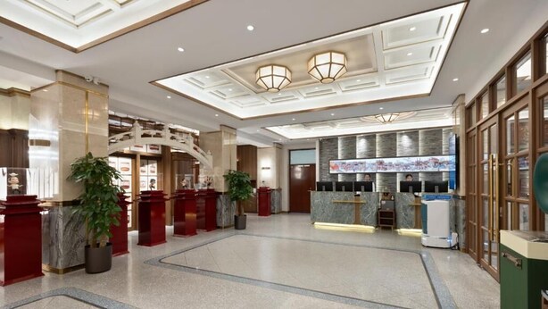 A spacious lobby with a central reception desk, a staircase, and a modern ceiling design. - Nostalgia S Hotel(beijing Tianqiao (Beijing)