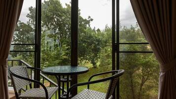 A room with a large window, two wicker chairs, and a glass table.