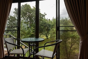 A room with a large window, two wicker chairs, and a glass table. - Mon View Ngarm (Chiang Mai)