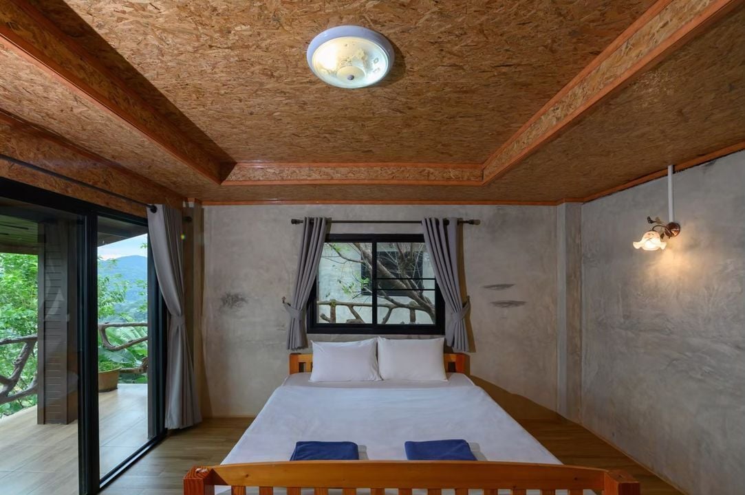 Un dormitorio con una cama grande, una ventana con cortinas, una lámpara en el techo y un balcón con vistas.