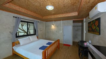 A bedroom with a wooden bed, a window with curtains, a desk with a chair, and an air conditioning unit.