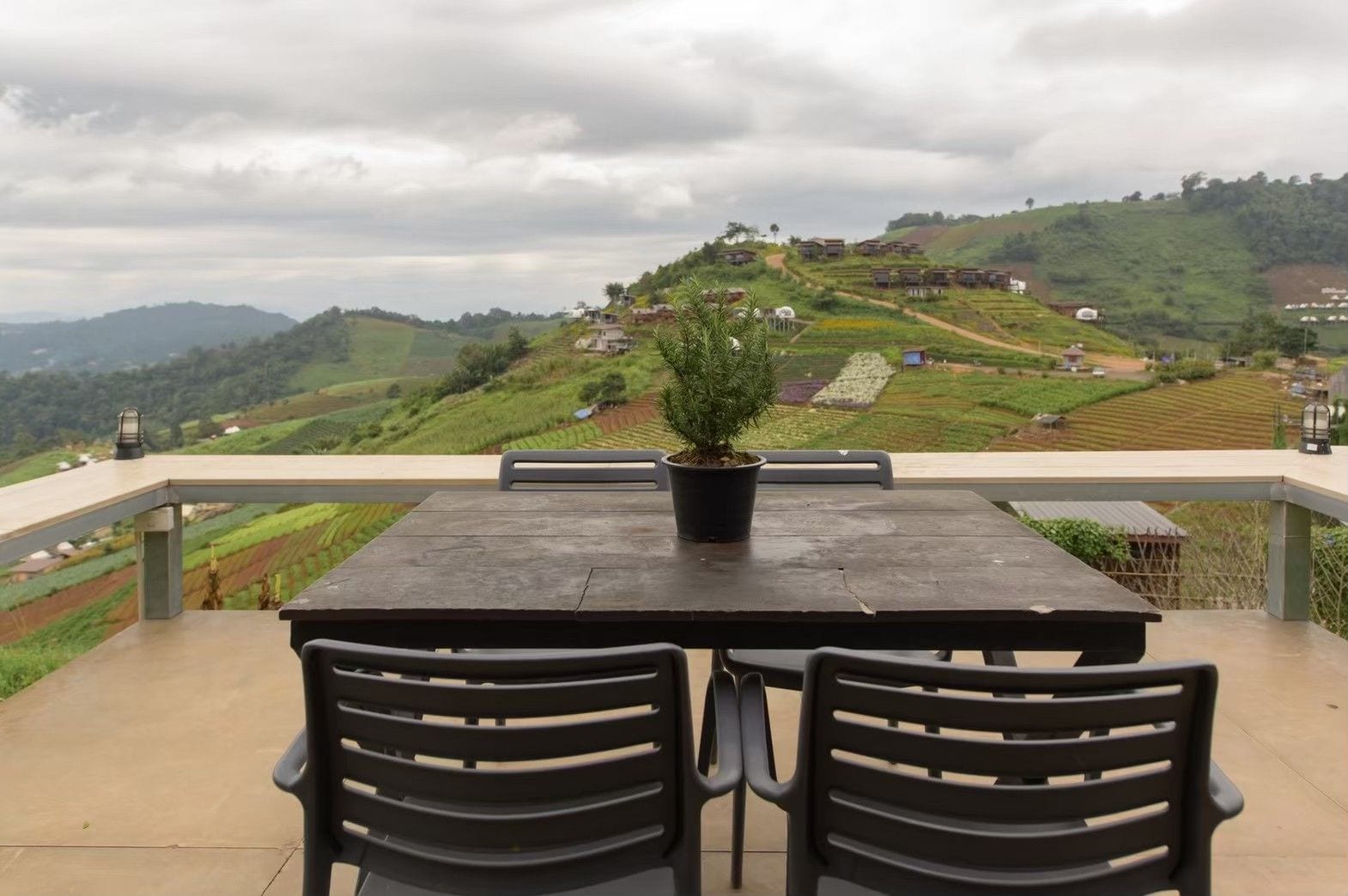 Un tavolo con sedie su una terrazza esterna con vista su campi a terrazze e colline.