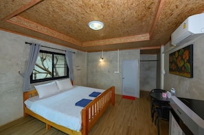 A bedroom with a wooden bed, a window with curtains, a desk with a chair, and an air conditioning unit.