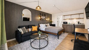 Eine moderne Wohnung mit Sofa, rundem Couchtisch, Bett, Küchenzeile und Esstisch.
