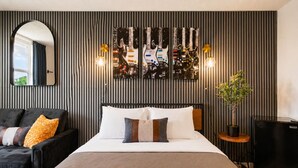 Ein modernes Schlafzimmer mit Bett, Stuhl, Topfpflanze und Wandleuchte.