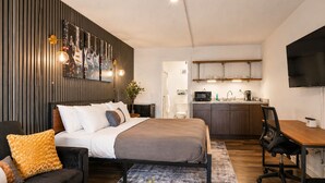 Ein modernes Zimmer mit Bett, einer Schlafcouch, einem Schreibtisch und einer Küchenzeile.