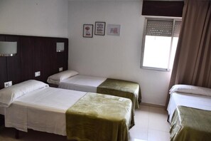 Ein Hotelzimmer mit zwei Einzelbetten, einem Fenster mit Jalousien und drei gerahmten Bildern an der Wand.