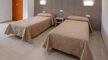 Ein Hotelzimmer mit zwei Betten, einer Holztür und Wandleuchten.