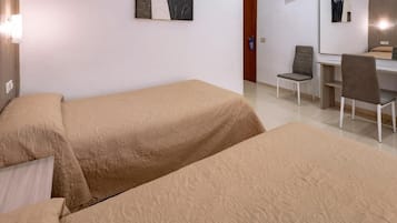 Una habitación con dos camas, un escritorio, una silla, un televisor y obras de arte en las paredes.