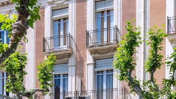 A multi-story building with balconies, windows, and trees.