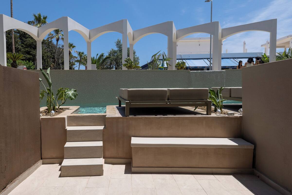 Ein Poolbereich mit einer Bank, Treppen und Blick aufs Meer.