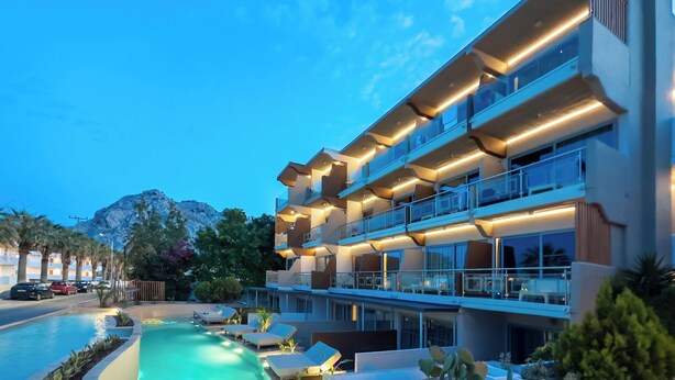 A multi-story hotel with a swimming pool, outdoor seating, and a mountain backdrop. - Kolymbia Bay Art Adults Only Boutique Hotel (Rhodes)