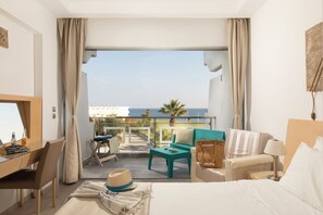 Ein Hotelzimmer mit Balkon, Schreibtisch, Bett und Meerblick.