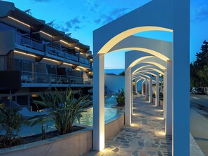 Um hotel moderno com área de piscina, espaço para sentar ao ar livre e vista para o mar.