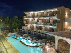 Ein mehrstöckiges Hotel mit Poolbereich, Außenbereich zum Sitzen und modernem architektonischen Design.