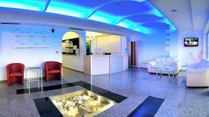 A modern lobby with a reception desk, seating area, and a decorative glass table. - Kolymbia Bay Art Adults Only Boutique Hotel (Rhodes)