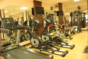 A gym with various exercise equipment, including treadmills and elliptical machines. - Panacea Suites Hotel (Alexandria)