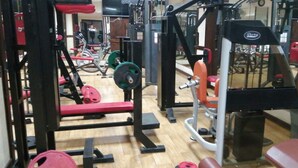 Un gimnasio con diversos equipos de ejercicio, entre ellos máquinas de pesas y pesas libres.
