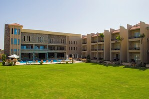 A hotel with a swimming pool, outdoor seating, and a well-maintained lawn. - Panacea Suites Hotel (Alexandria)