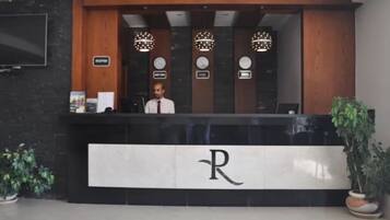 A reception desk with a sign indicating 'Reception,' three clocks above it, and a logo with a capital 'R' on the wall.