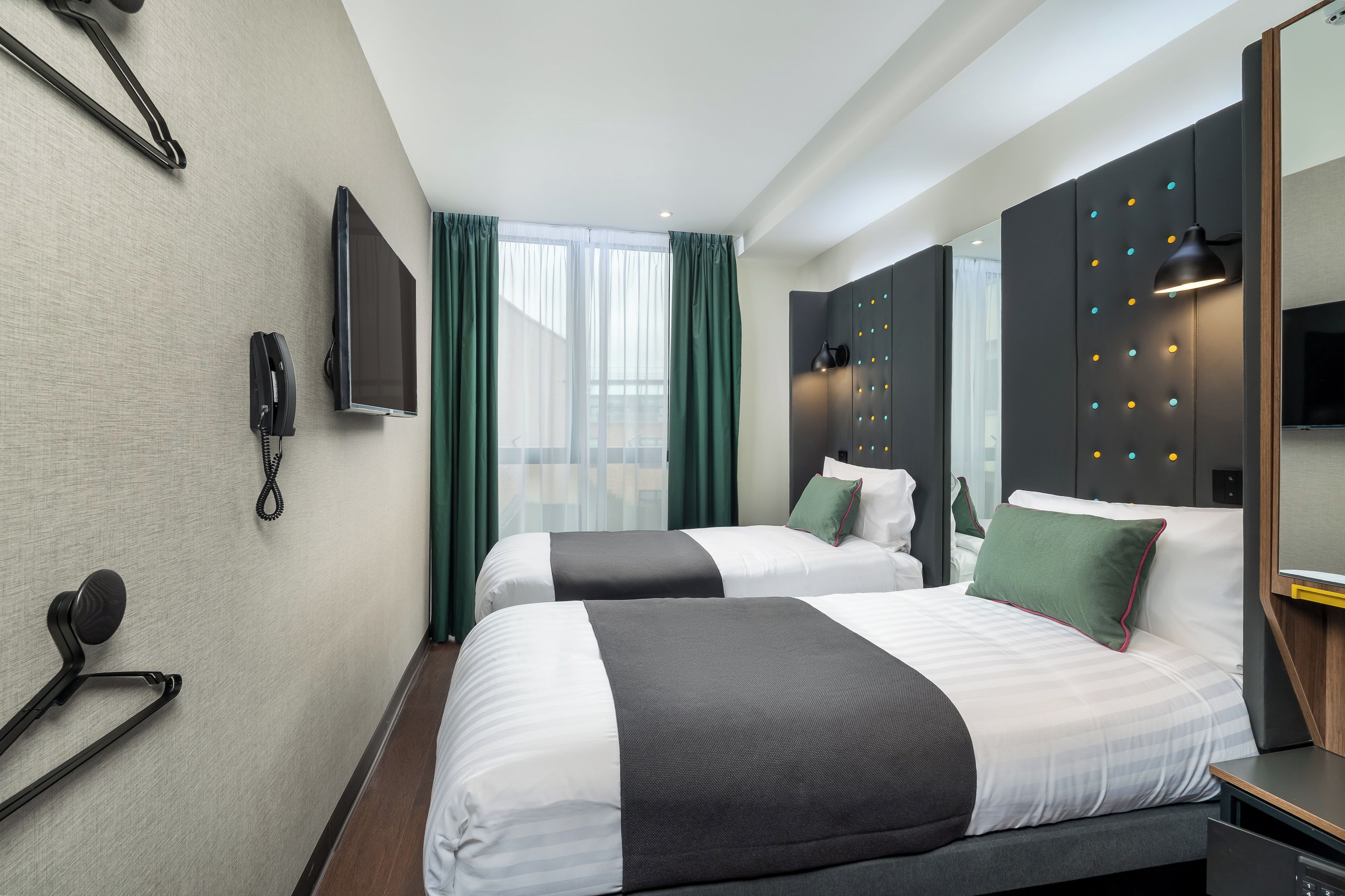 Habitación de hotel con dos camas, televisión, teléfono y espejo.